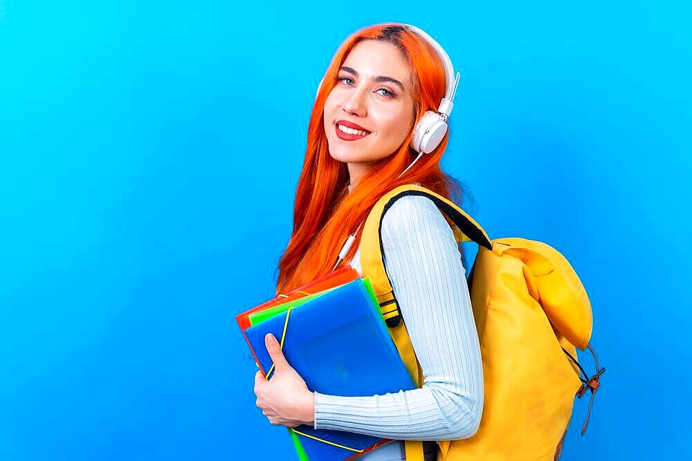 Redhead woman in studio photography dancing college student on a blue background, back to school