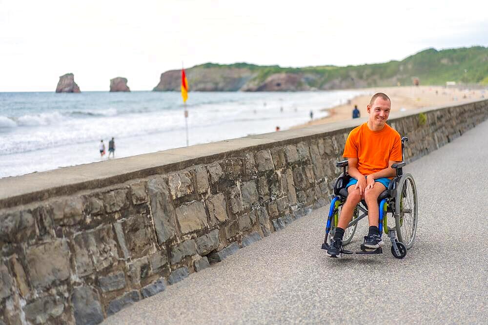 A disabled person in a wheelchair by the beach, having fun in summer