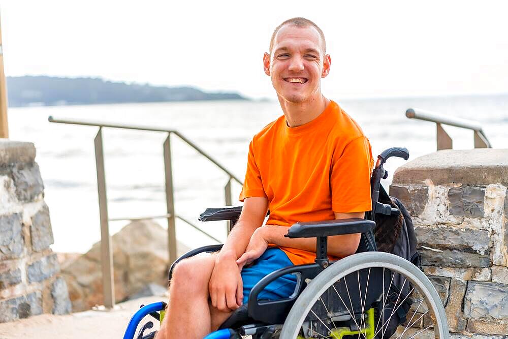 Portrait of a disabled person in a wheelchair at the beach on summer vacation smiling