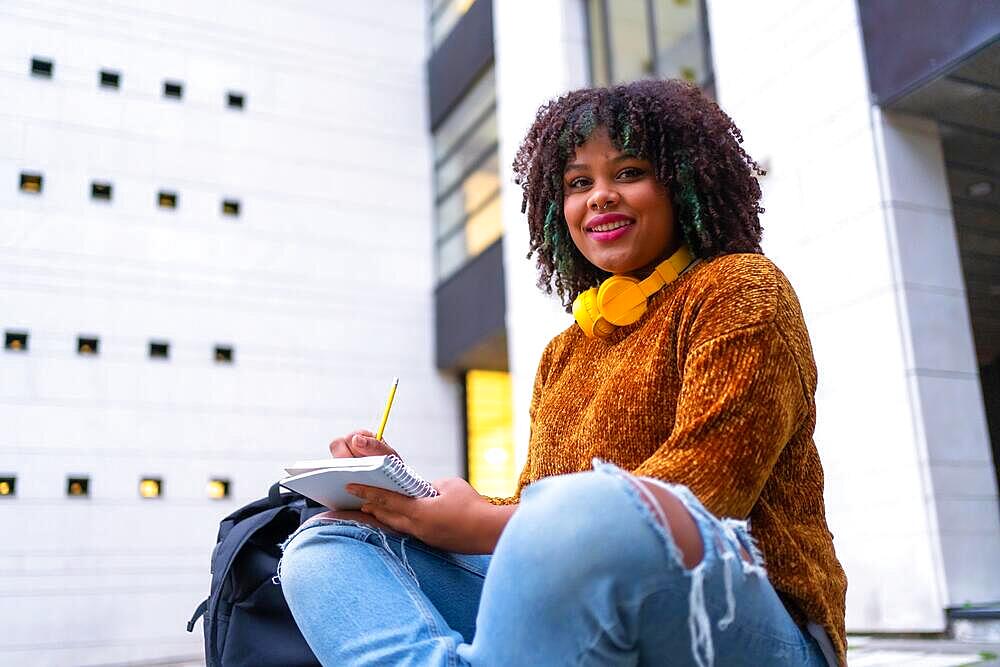 Portrait of black ethnic girl sitting in college doing classwork or studying for an exam on back to school