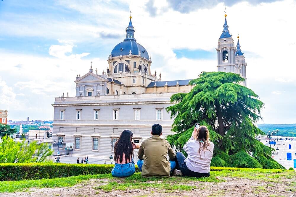 Tourist friends visiting Madrid city on summer vacation. Sitting looking at the Almudena