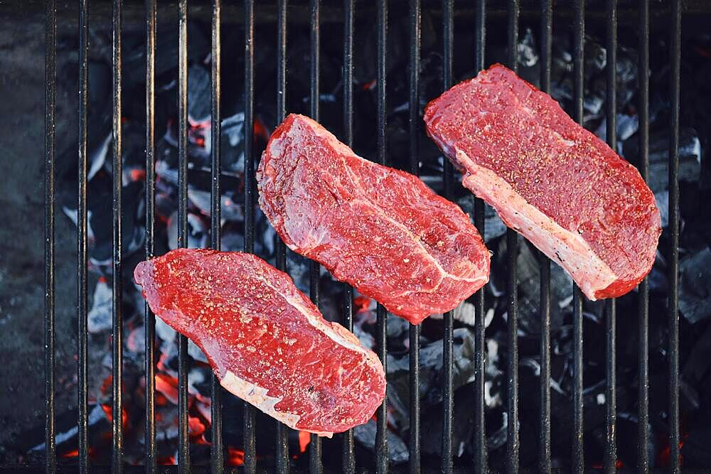 Top view of beef strip steaks on grid of grill