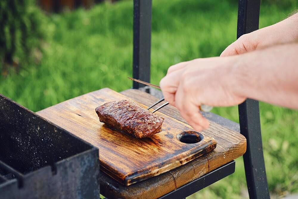 Unrecognizable man takes out juicy club steak from grill