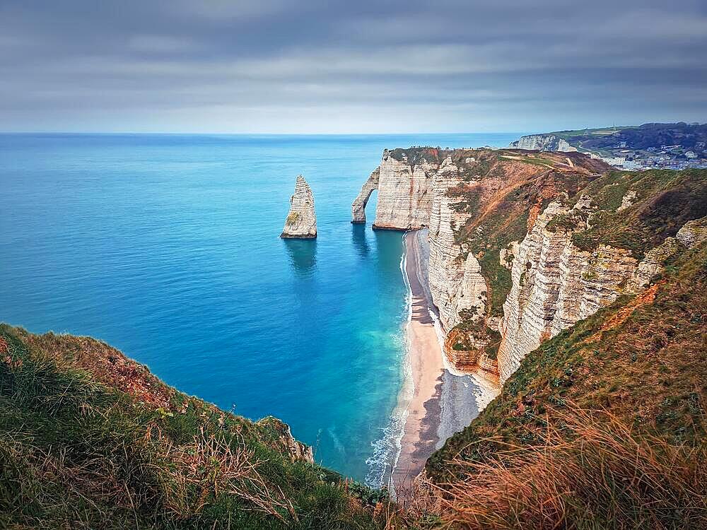 Sightseeing view to the famous rock Aiguille of Etretat in Normandy, France. Limestone cliffs Falaise d'Aval washed by La Manche channel waters. Beautiful coastline scenery