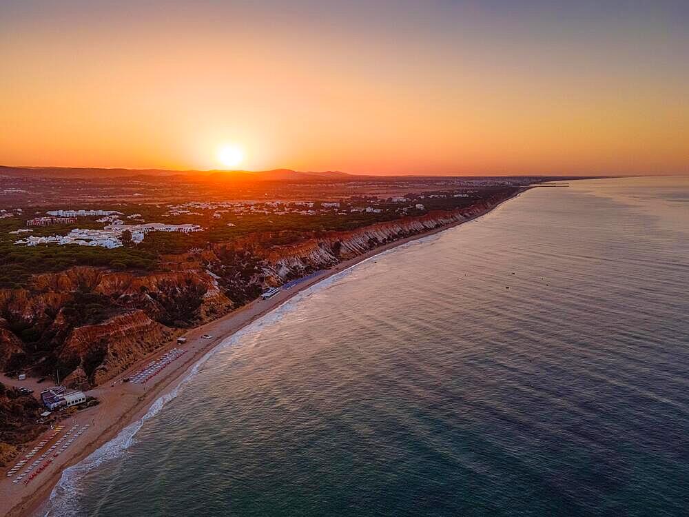 The sun rises behind the beach of Falesia, in the district of Faro, near the town of Albufeira. (Aerial photo taken with a drone), Algarve, Falesia, Faro, Portugal, Europe