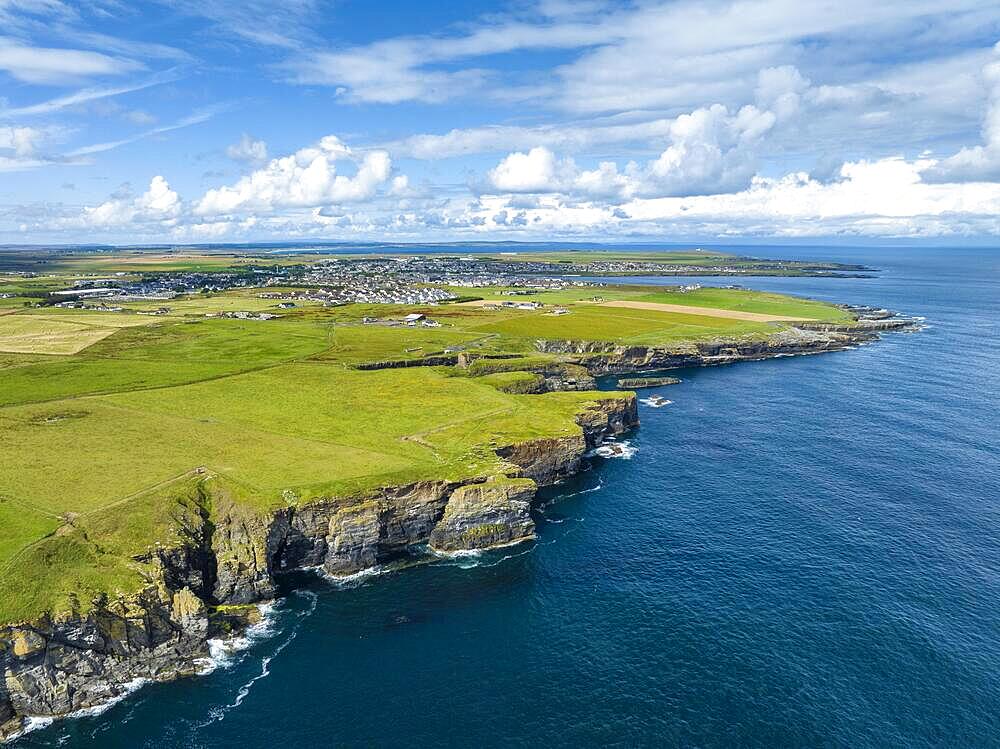 Aerial view of rugged cliffs on the North Sea coast, with the harbour town of Wick on the horizon, County Caithness, Scotland, United Kingdom, Europe