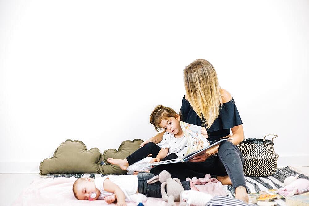 Woman girl reading book near baby