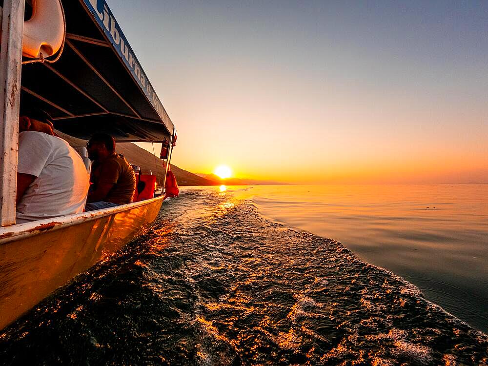 View from below along the orange sunset water of Shkoder Lake in Shiroka from a tourist boat. Albania