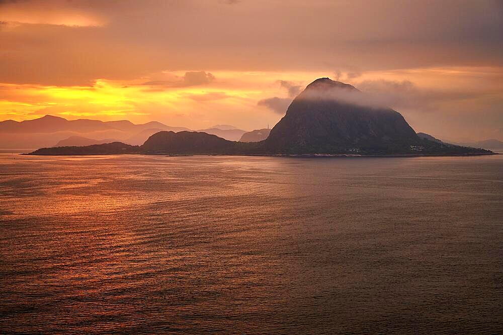 Rock Hessa nearby Alesund Norway in the ocean with clouds in sunrise