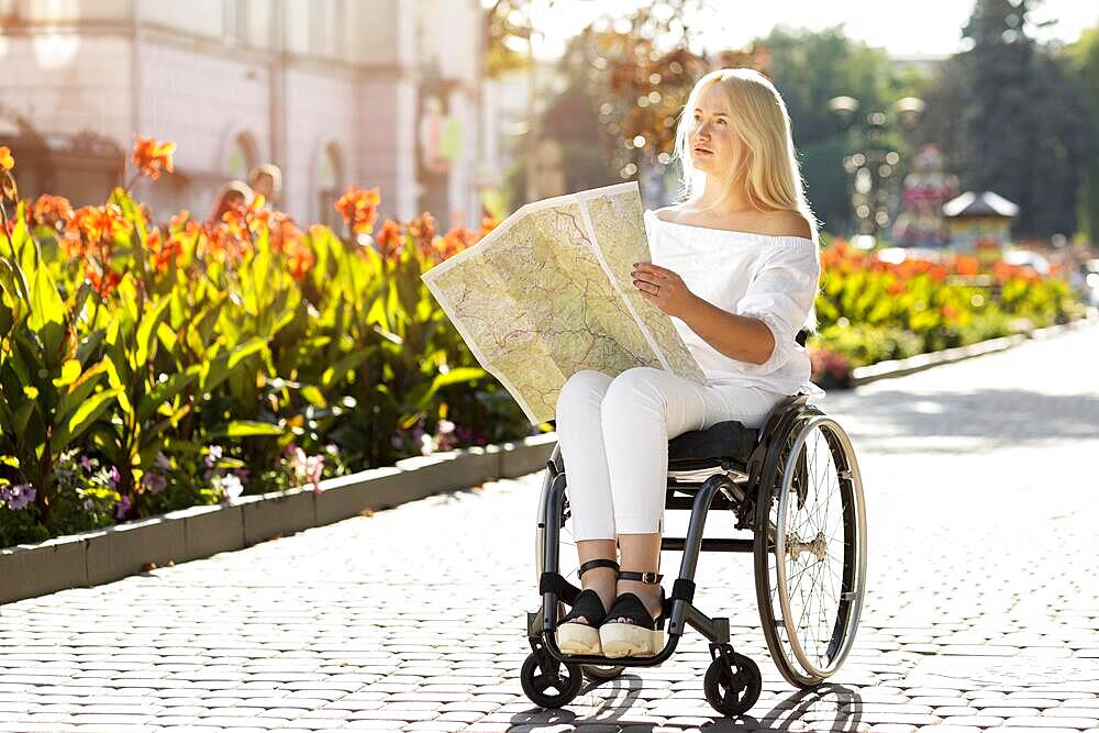 Woman wheelchair looking map outdoors