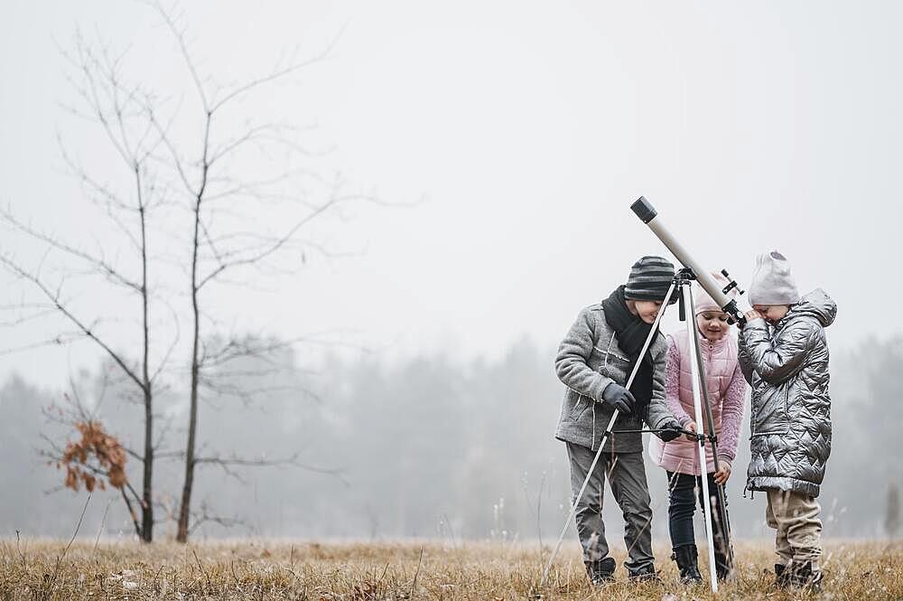 Kids using telescope outside with copy space