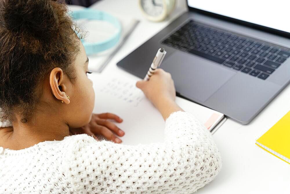 Little girl attending online school home using laptop