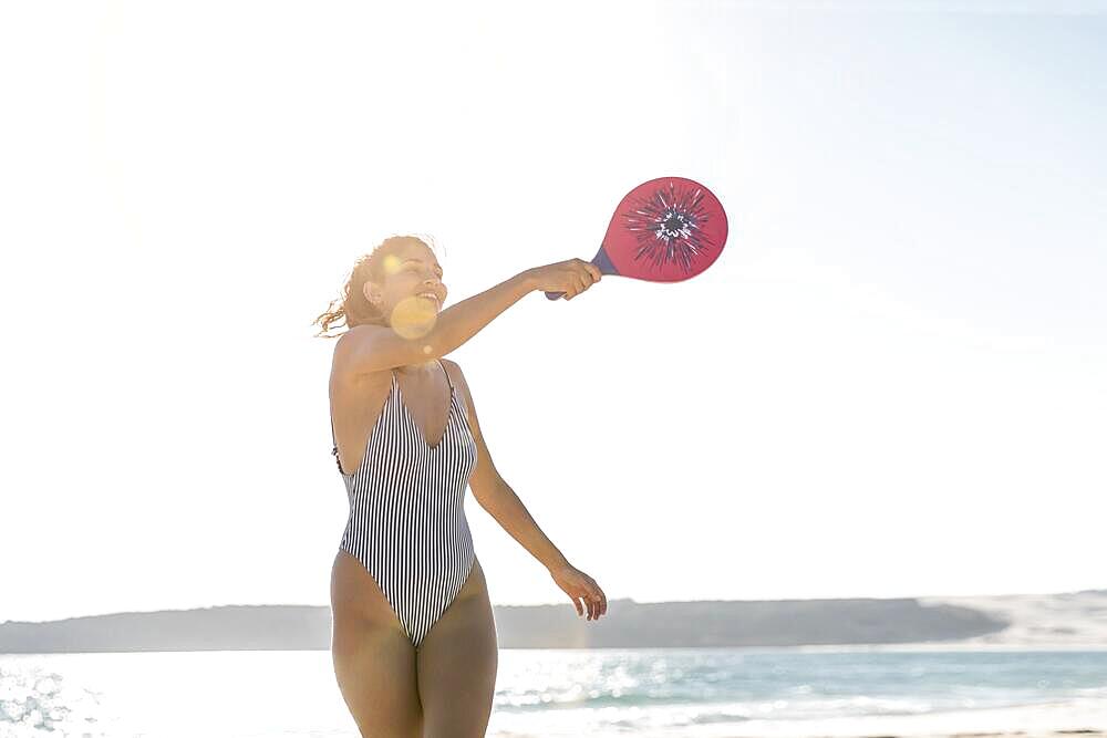 Smiling young woman beach playing tennis