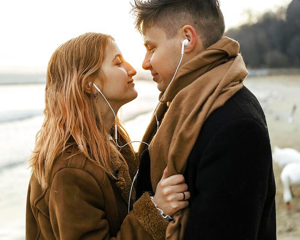 Couple listening music earphones beach winter