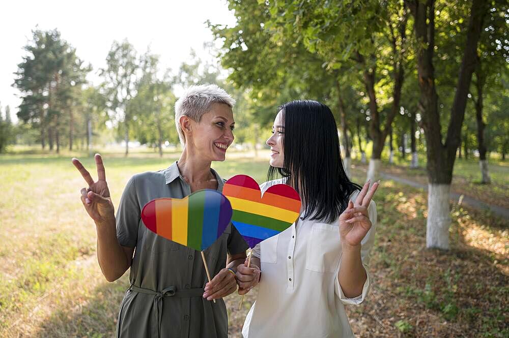 Lesbian couple holding lgbt heart shape flag