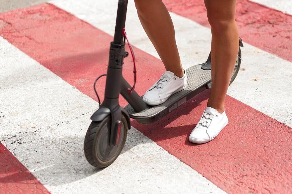 Woman with tennis shoes riding scooter