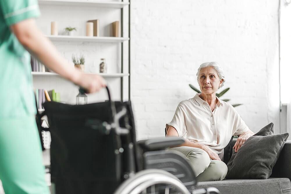 Nurse holding wheelchair front senior female patient