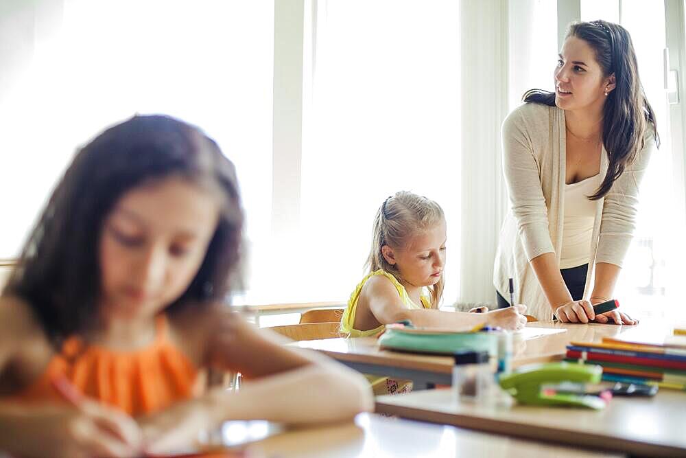 Female teacher leaning upon table looking away