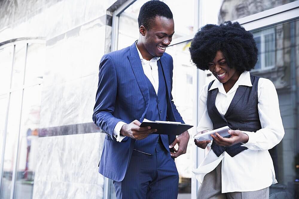 Smiling african young businessman businesswoman holding clipboard digital tablet