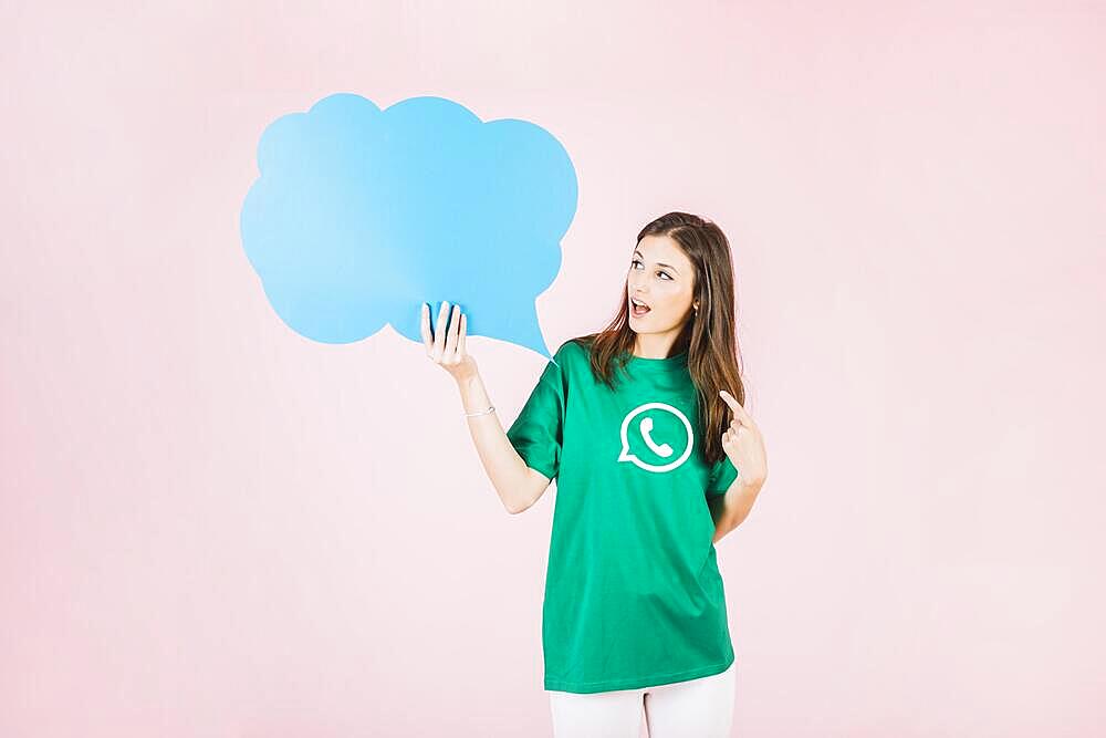 Young woman holding empty blue speech bubble pink background