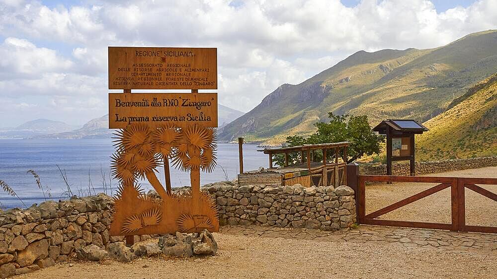 Welcome sign, stone wall, green mountains, cloudy sky, Zingaro, national park, nature reserve, northwest, Sicily, Italy, Europe