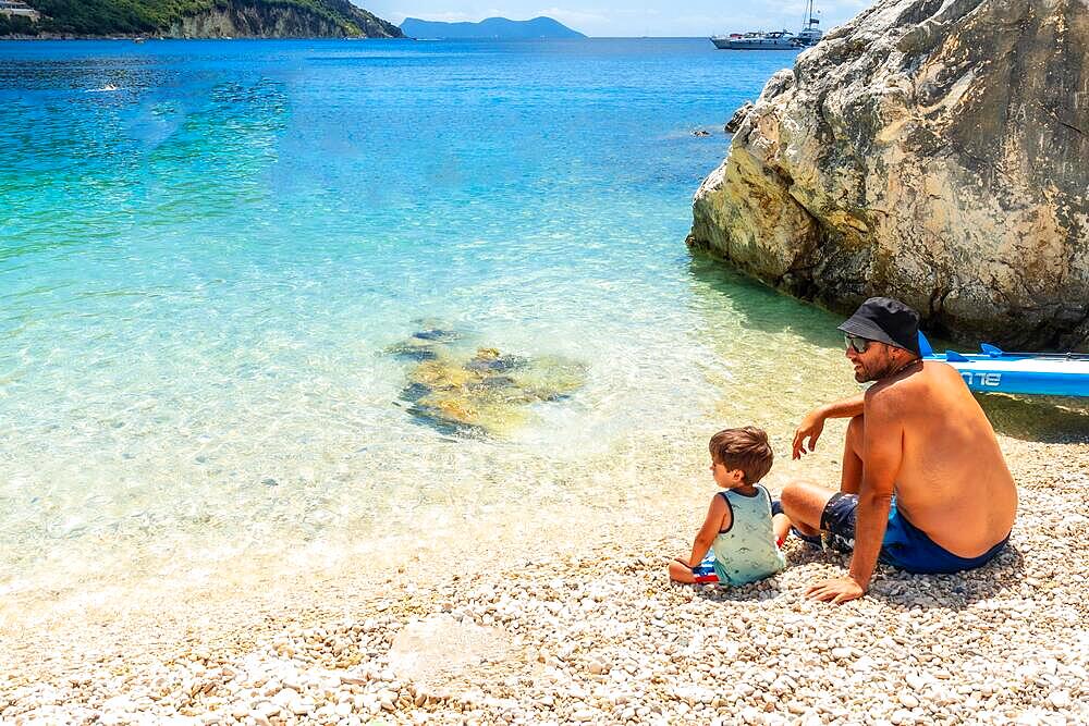 Father and son playing on the beach of Paralia Mikros Gialos in Lefkada. Greece