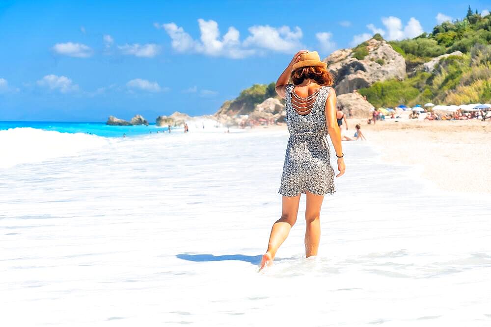 Woman walking through the water at Megali Petra beach with turquoise water of Lefkada island, Ionian Sea, Greece, Europe