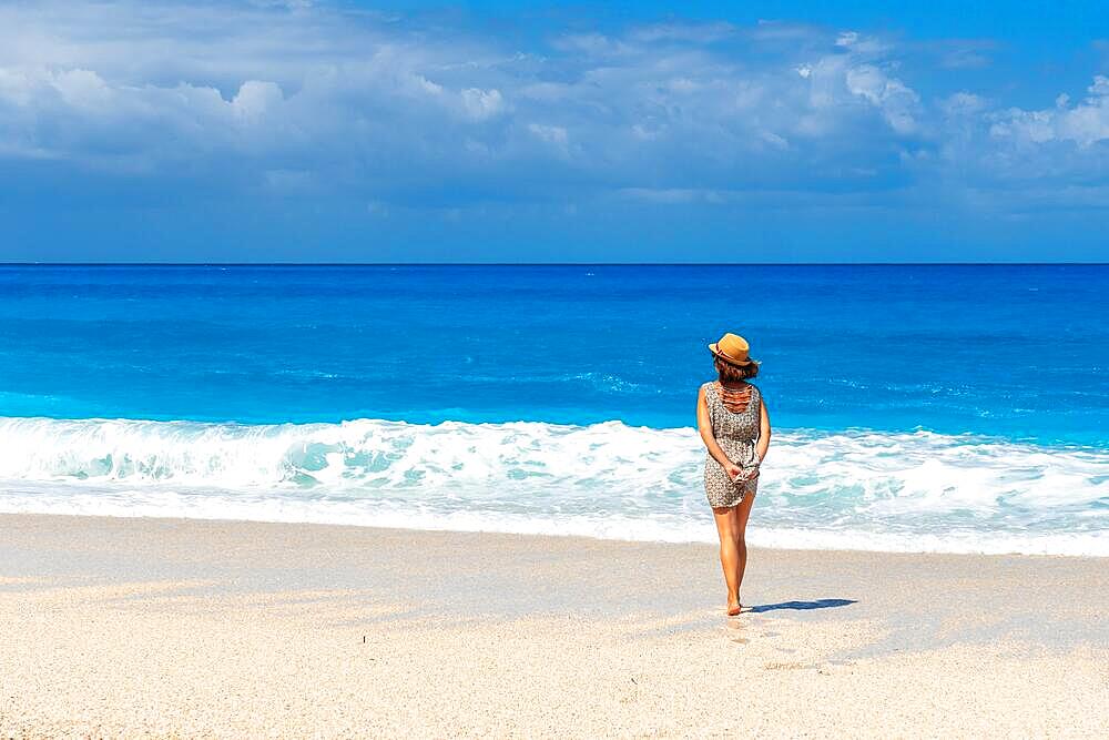 Thoughtful woman looking at the sea at Megali Petra beach with turquoise water of Lefkada island, Ionian Sea, Greece, Europe