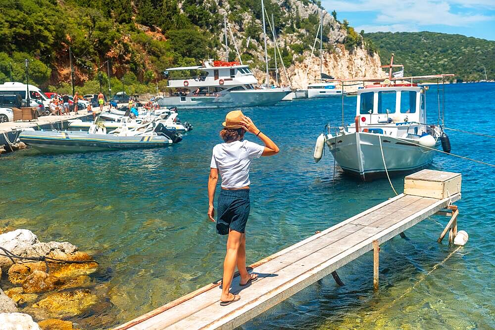 Portrait of a woman walking on a wooden footbridge in the port of Frikes on the island of Ithaki or Ithaca, Ionian sea, Greece, Europe