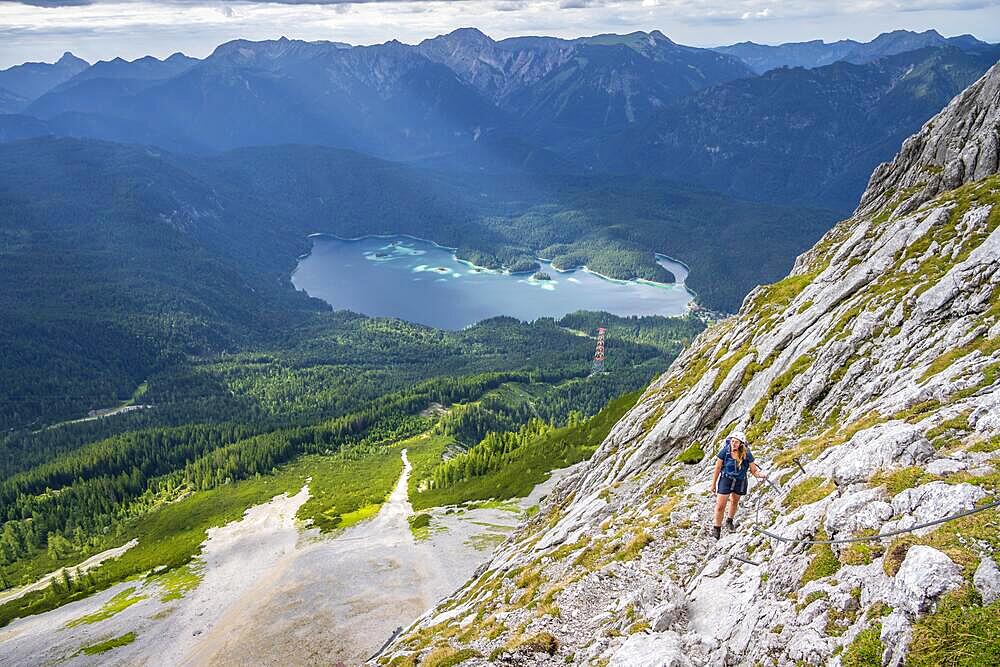 Via ferrata over the Riffelscharte, hiker in the mountains, view of Eibsee lake and Werdenfelser Land, Wetterstein Mountains, Garmisch-Patenkirchen, Bavaria, Germany, Europe