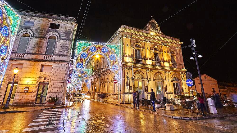 Night shot, illuminated historical buildings, festive street lighting, rain-soaked street, cars, passers-by, Scigli, baroque town, baroque angle, southeast, Sicily, Italy, Europe