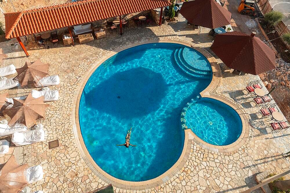 Aerial shot of a swimming pool with a woman bathing enjoying the holidays