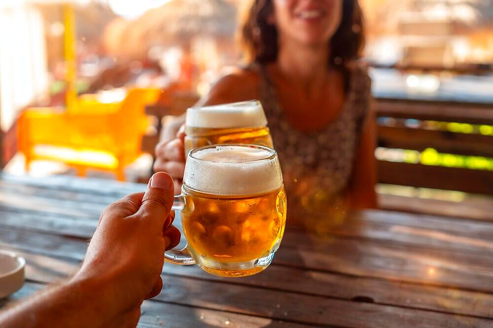 Toast of a couple on the beach in summer drinking a few beers in a celebration of friendship