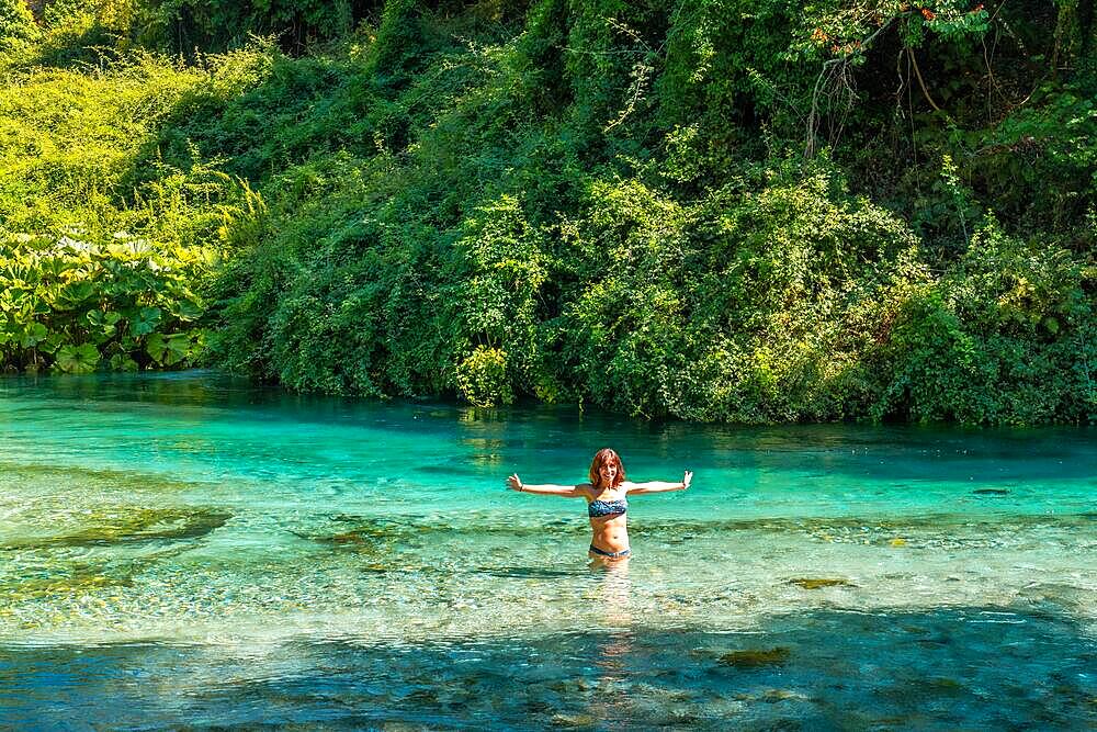 A tourist bathing smiling in the cold waters of the river of The Blue Eye or Syri i kalter in the mountains of southern Albania