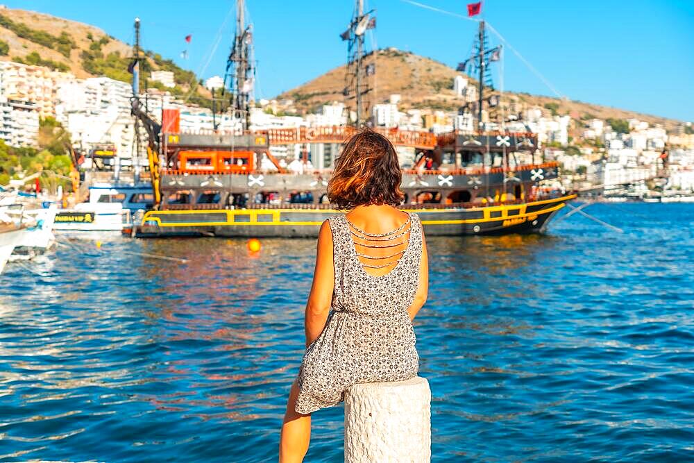 Woman looking at tourist boats at Saranda Beach on the Albanian Riviera in Sarande on Bulevardi Hasan Tahsini, Albania, Europe