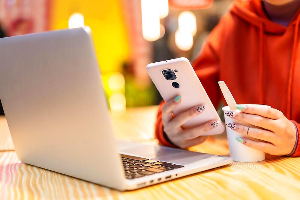 Alternative unrecognizable person with a hot coffee surfing the internet on the computer and sending a text message