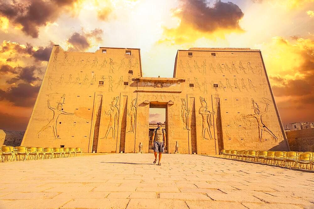 A young tourist entering the Temple of Edfu in the city of Edfu, Egypt. On the bank of the Nile river, geco-Roman construction, temple dedicated to Huros