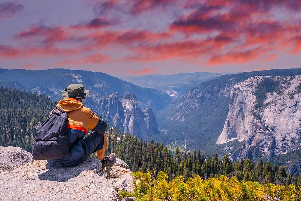 A young winged seated Taft point looking at Yosemite National Park and El Capitan in sunset. United States