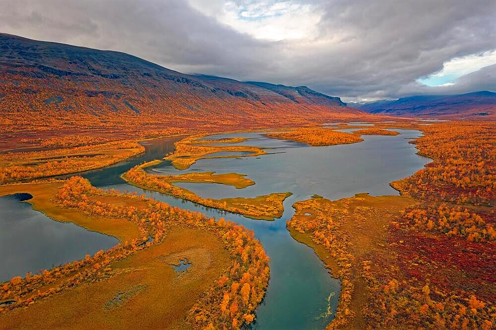 Drone shot, view of the valley Vistasvagge with the meandering river Vistasjakka and countless small lakes, birch forests, intense colouring, autumn, mountain landscape in the background, Nikkaluokta, Kiruna, Gaellivare, Norrbottens laen, Lapland, Northern Sweden, Sweden, Europe