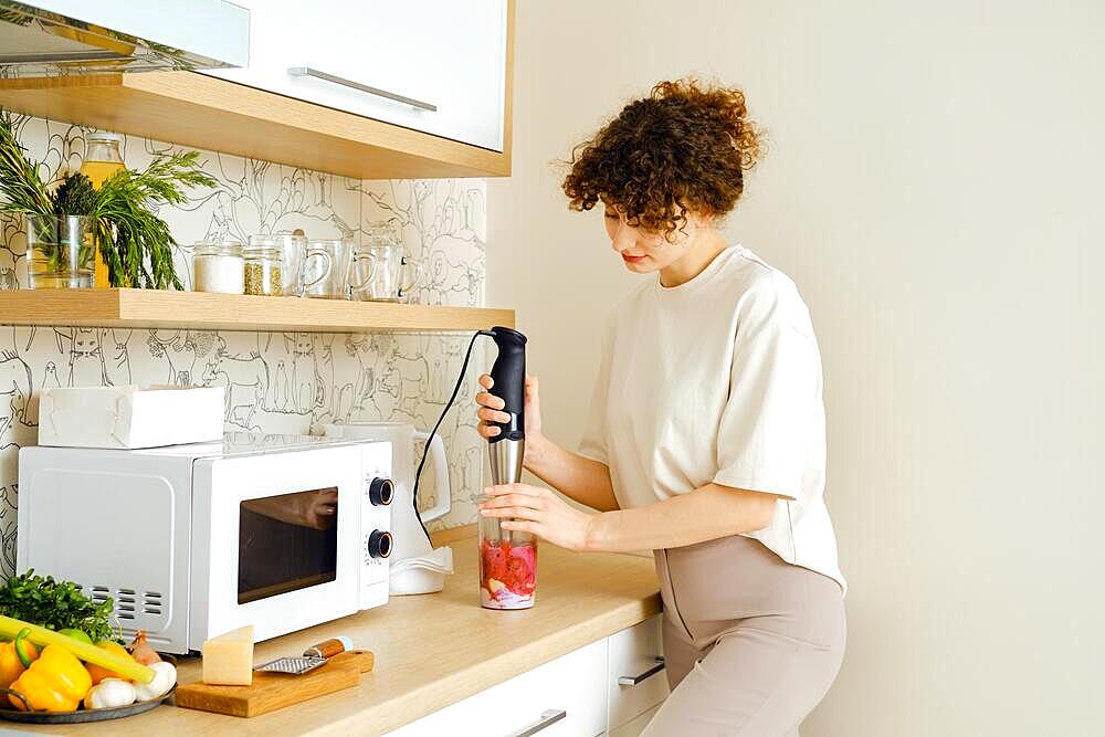 A woman mixing fruits and berries in a blender for smoothie