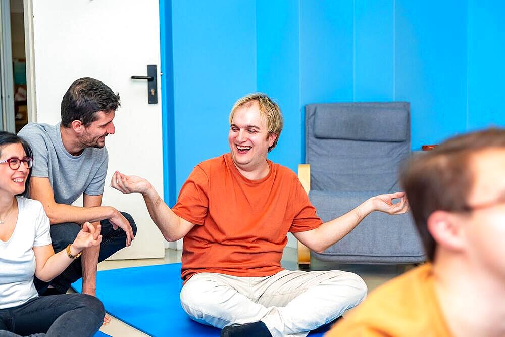 Instructor and disabled man smiling and talking during yoga class