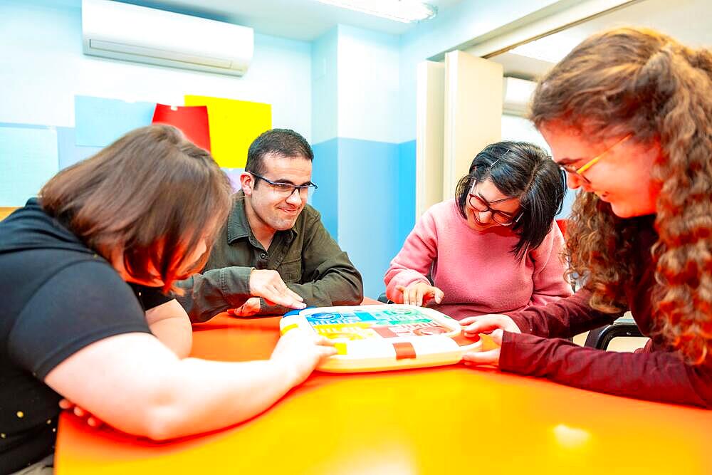 Group of disabled people playing board games together having fun in a day centre for people with special needs