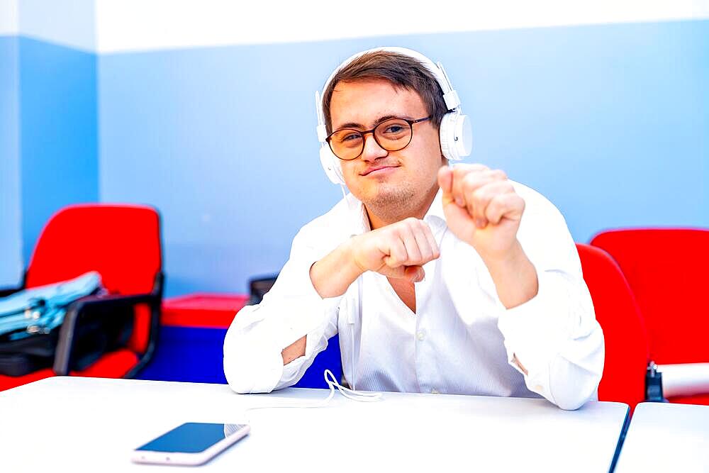 Man with down syndrome listening to music with phones sitting indoors