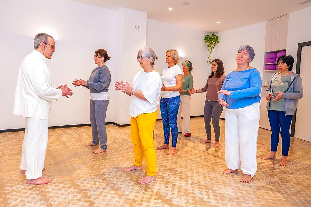 Qi gong instructor and women closing eyes and breathing during a indoor class