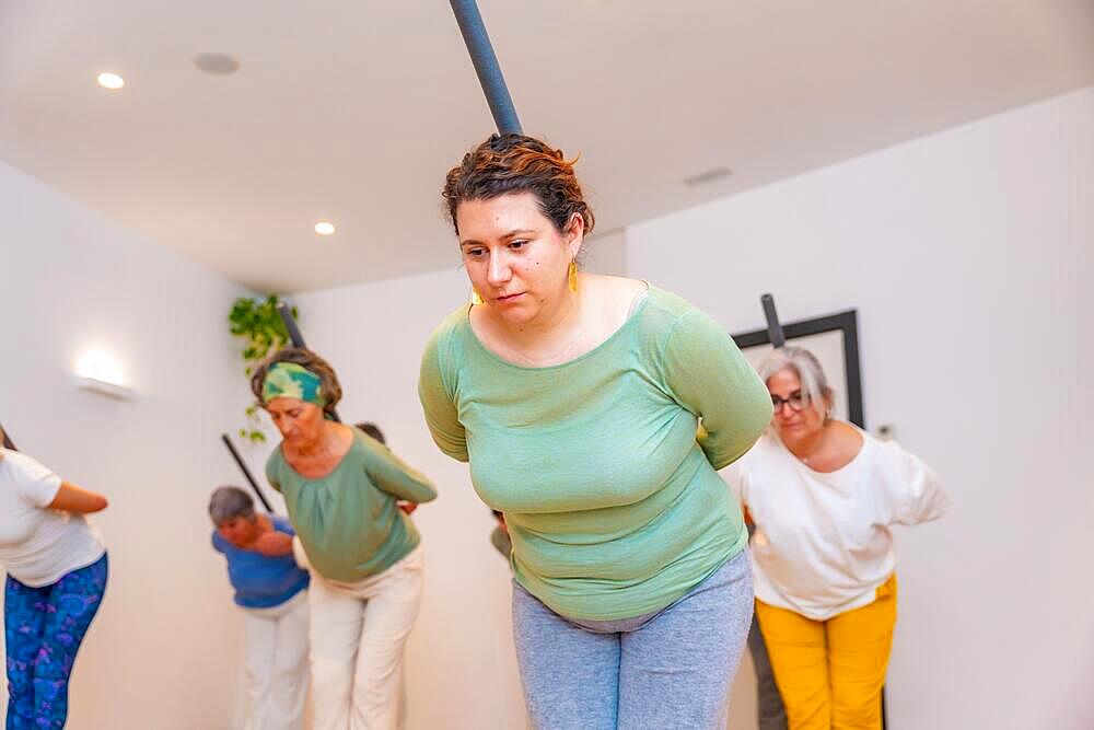 Women stretching the back helped by a tube in a qi gong class