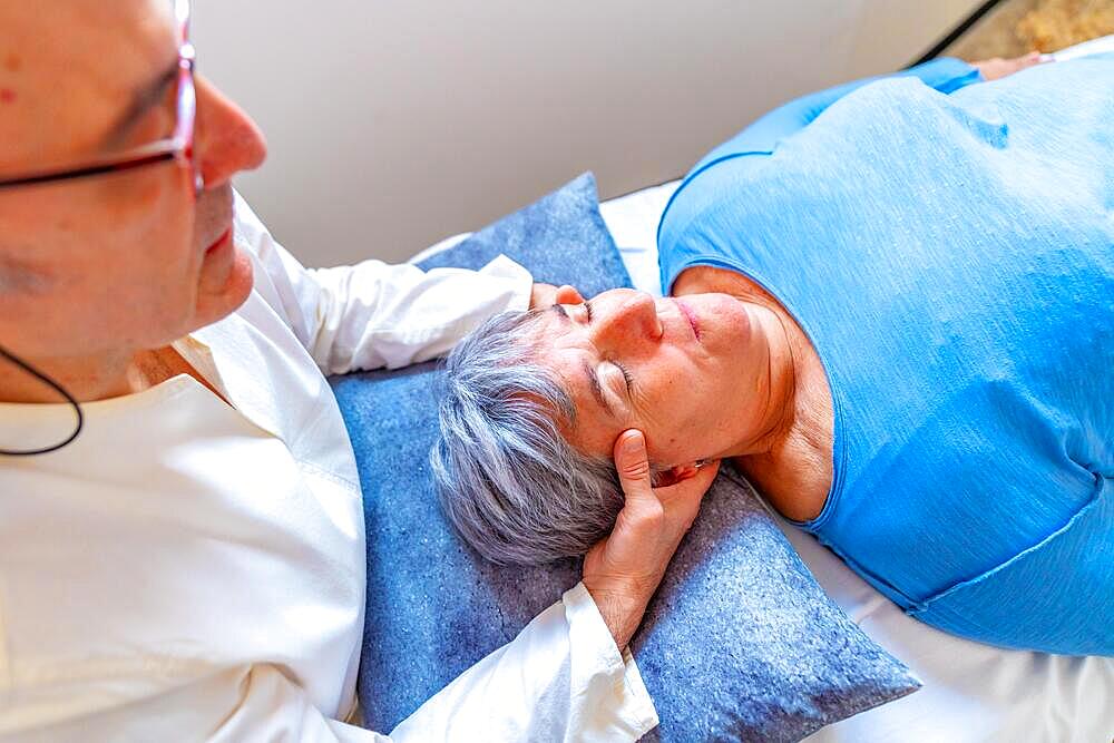 Qi gong masseur doing a massage to the head of a mature woman