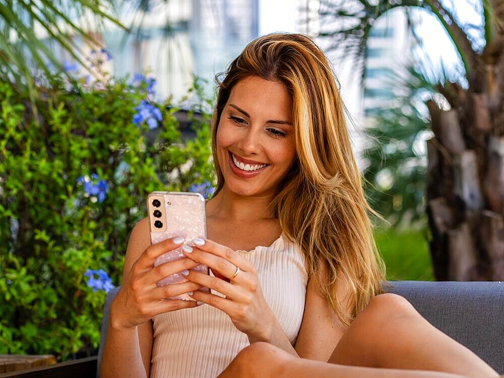 Close-up of a beautiful woman sitting on a sofa while writing a message on her smartphone