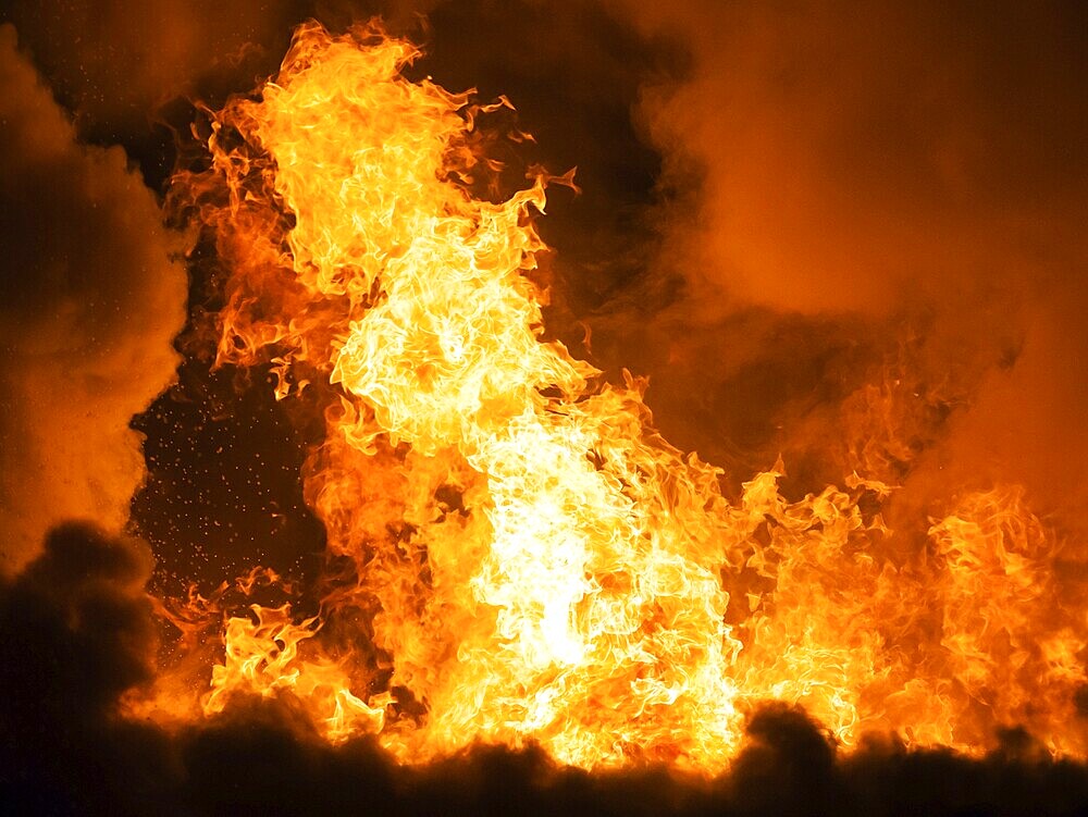 Arson or nature disaster, burning fire flame on wooden house roof