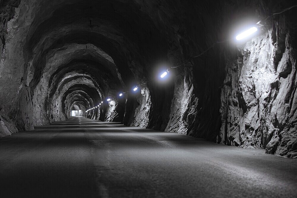 A long, gloomy tunnel with illuminated rock faces and a tarmac path, Zillertal, Austria, Germany, Europe