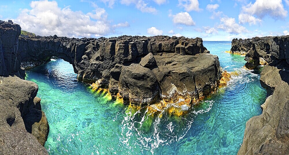 Rugged lava rock formations with a natural arch over a turquoise sea under a blue sky, A Porta do Diabo, Sao Miguel Island, Azores, Portugal, Europe